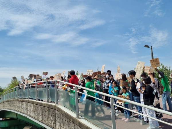 (사)소비자기후행동과 부천지역시민단체 회원들이 4월 22일 ‘지구의 날’을 날을 맞아 중앙공원에서 상동호수공원까지 행진하며 캠페인을 벌이고 있다. 사진은 상동보행육교를 지나며 피켓을 들어보이는 장면.